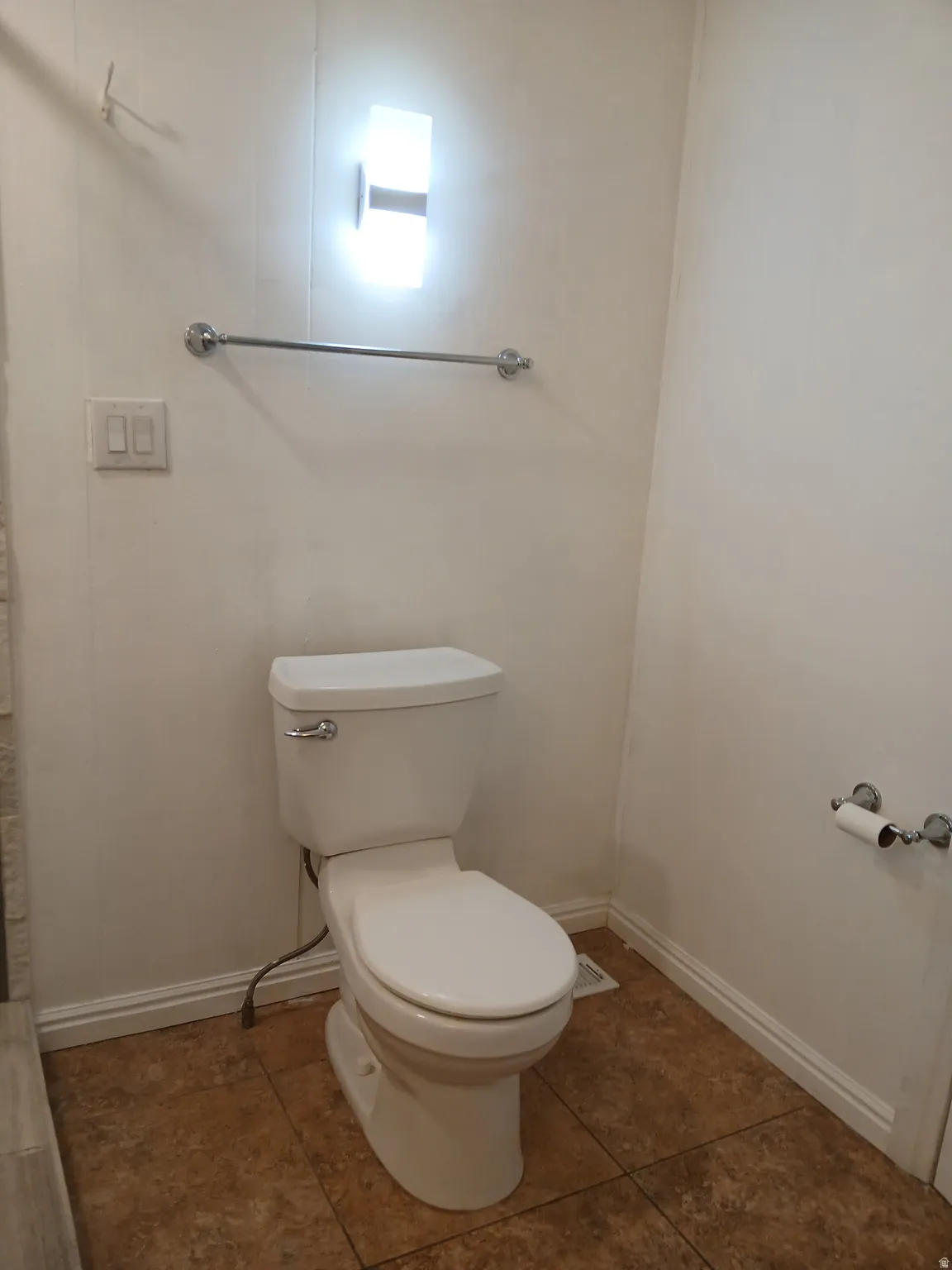 Bathroom featuring toilet and dark tile patterned floors