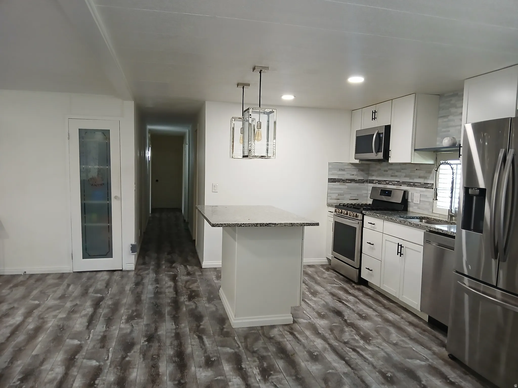 Kitchen with white cabinets, appliances with stainless steel finishes, dark stone countertops, and recessed lighting