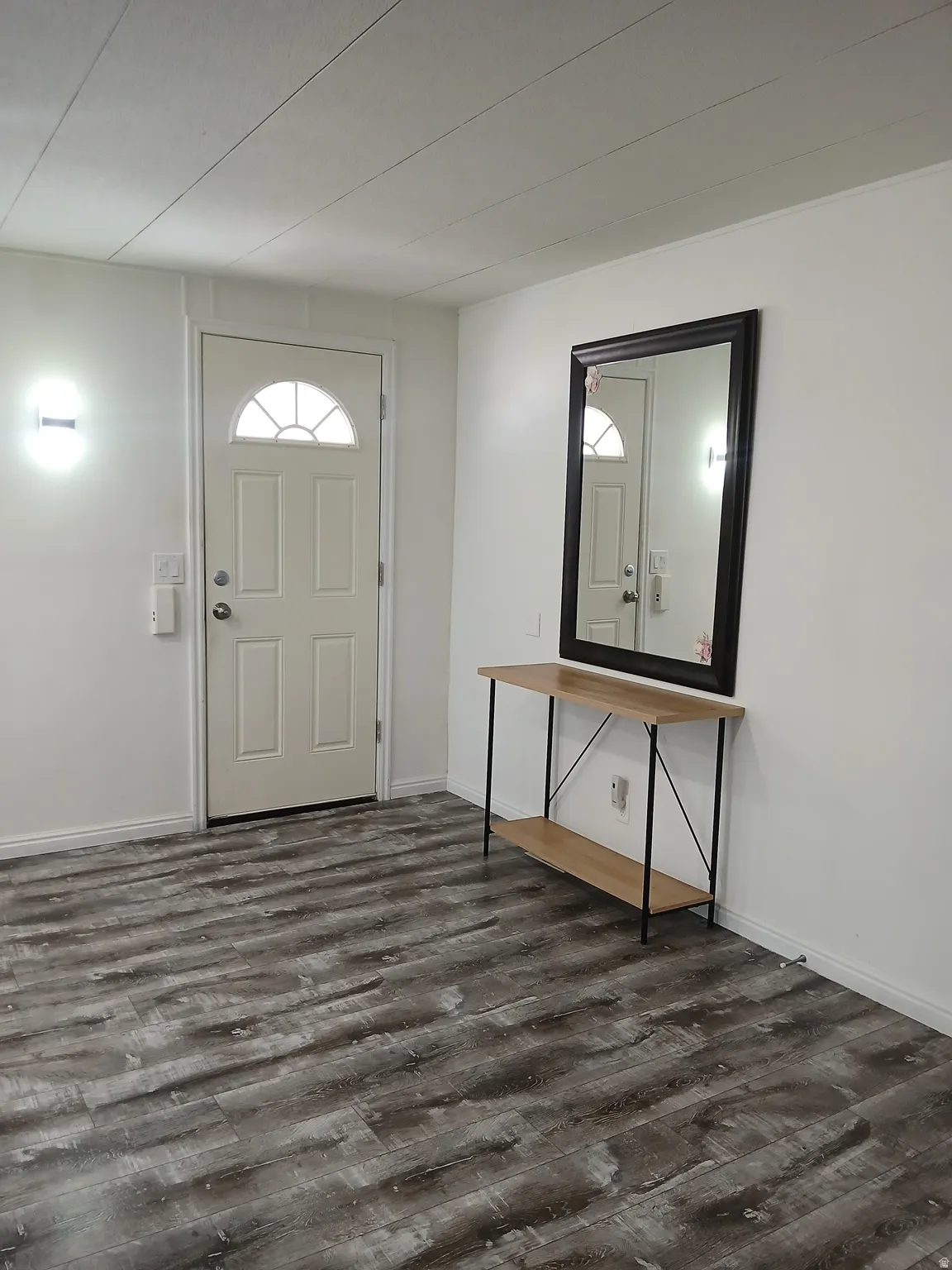 Foyer entrance with dark wood-type flooring and baseboards
