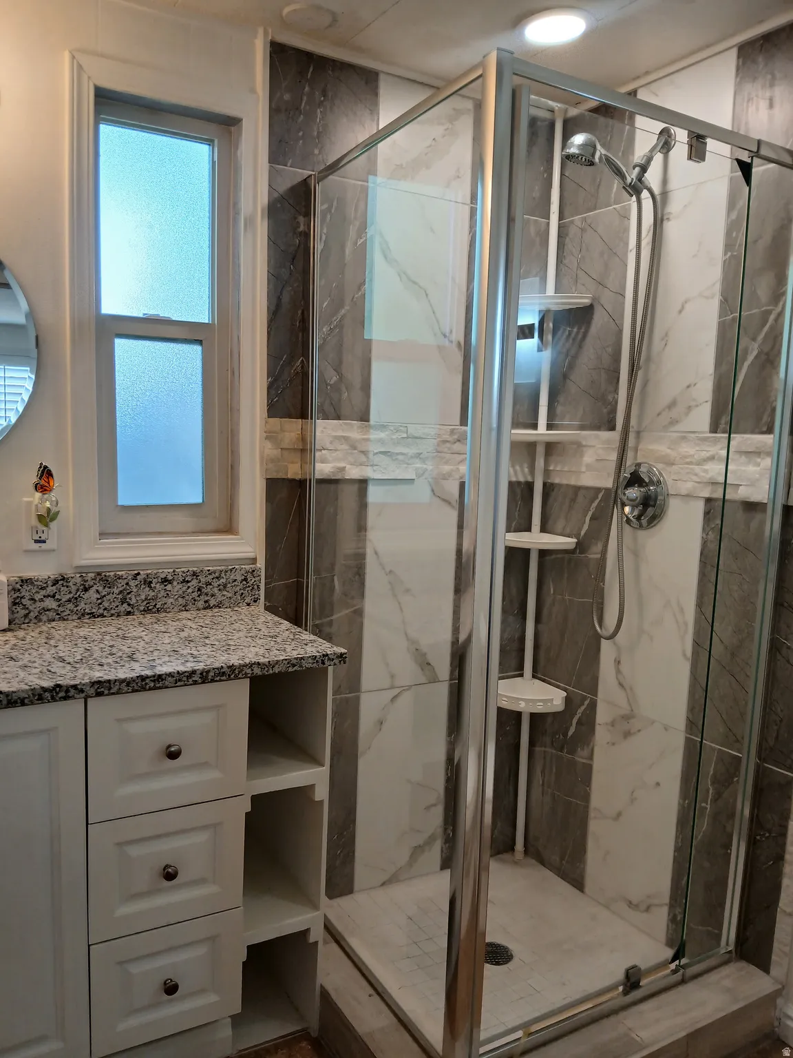 Full bath featuring a marble finish shower and vanity