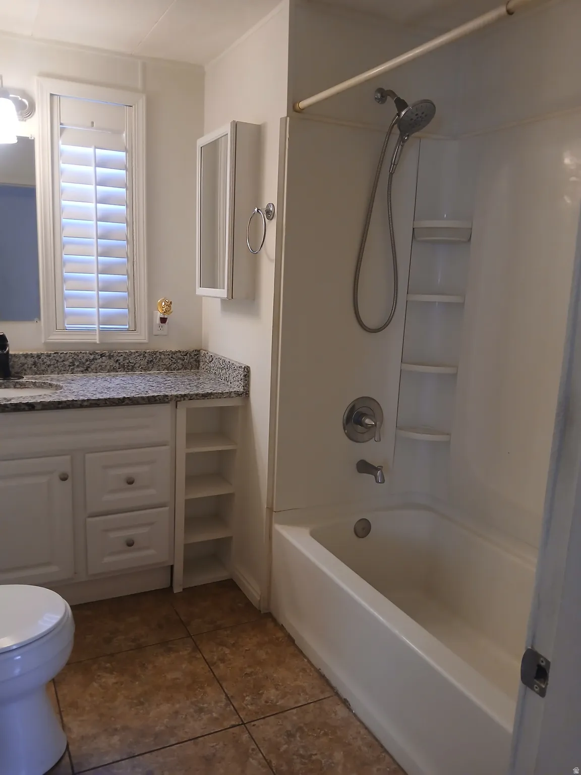 Full bath with shower / bath combination, vanity, and dark tile patterned floors