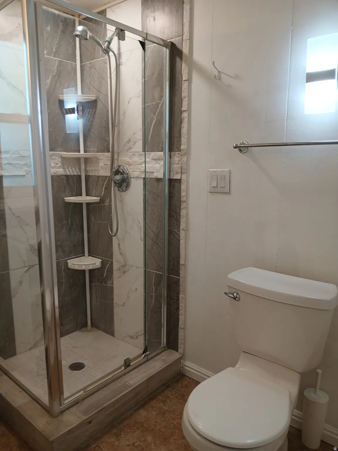 Full bathroom with toilet and a marble finish shower