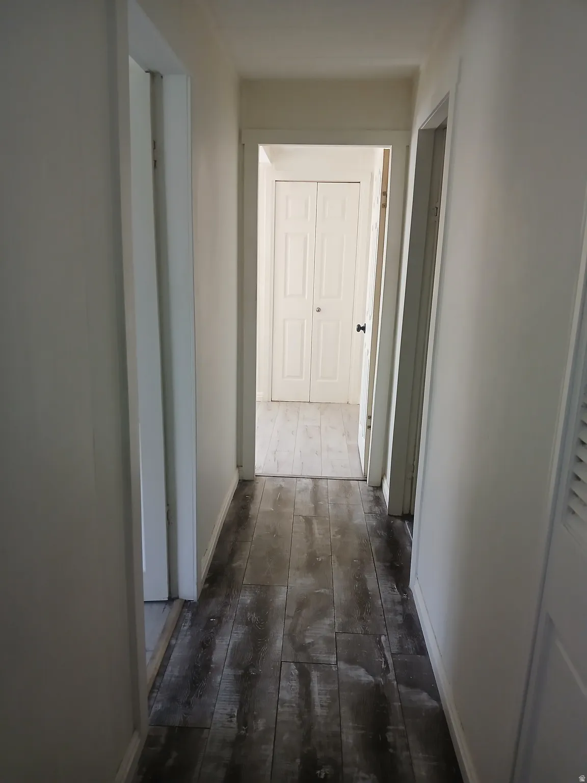 Hallway featuring dark wood-style floors and baseboards