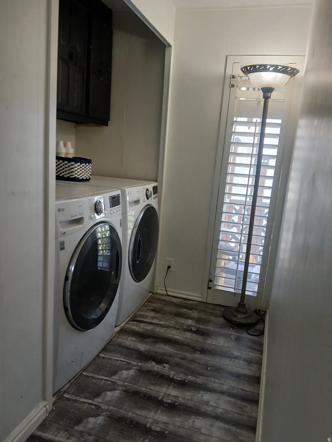 Washroom with independent washer and dryer, dark wood finished floors, and cabinet space