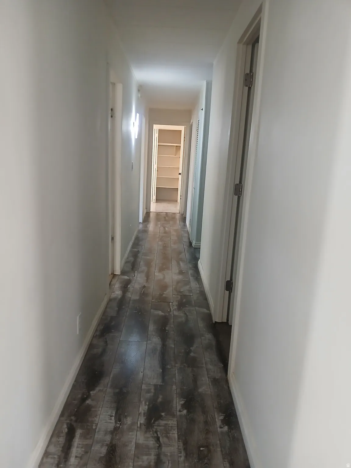 Hallway with dark wood-type flooring and baseboards