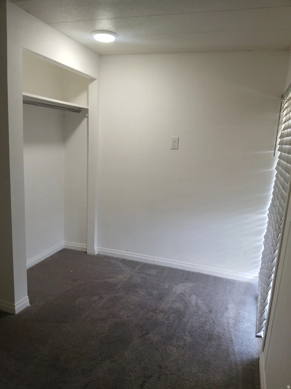 Unfurnished bedroom with dark colored carpet and a closet