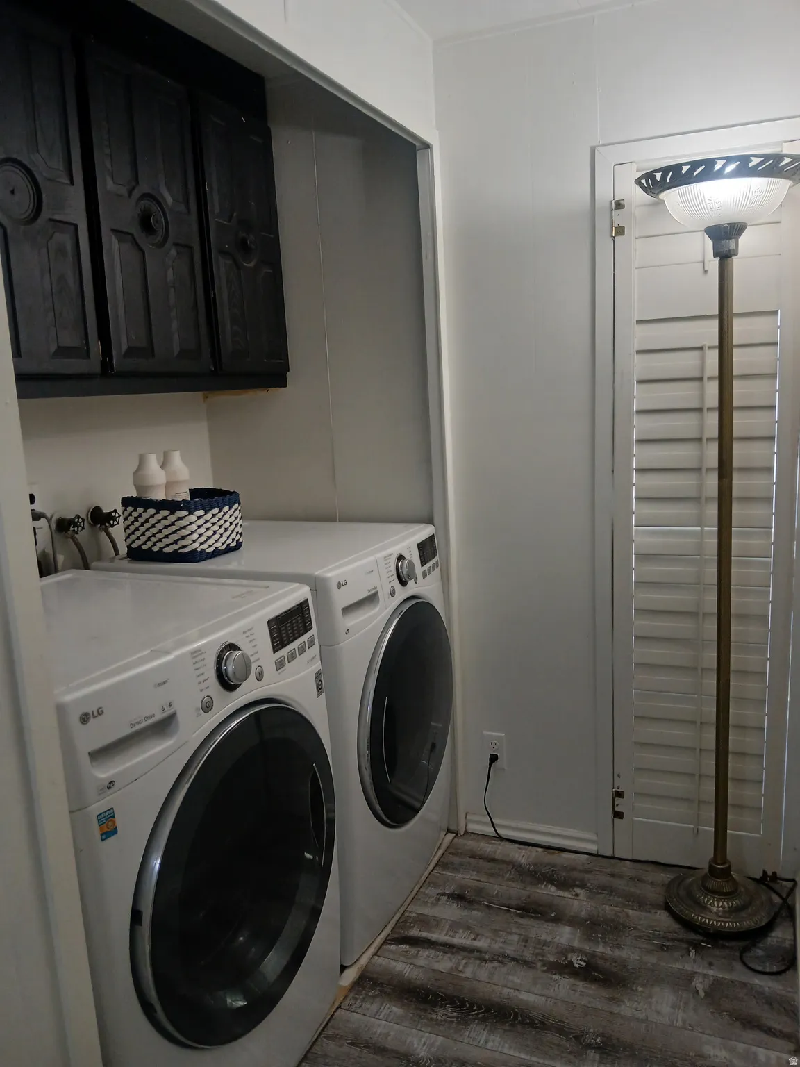 Laundry room with dark wood-style floors, separate washer and dryer, and cabinet space