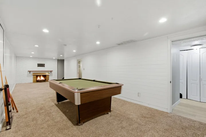 Recreation room with a brick fireplace, recessed lighting, pool table, and light colored carpet