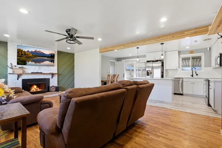 Living area featuring light wood finished floors, a fireplace, recessed lighting, a ceiling fan, and a chandelier
