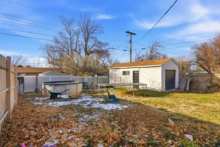 Fenced backyard featuring a trampoline and an outdoor structure