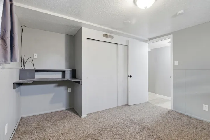 Unfurnished bedroom featuring a textured ceiling, a closet, and light colored carpet