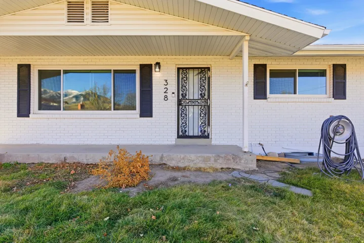 Entrance to property with a porch and brick siding