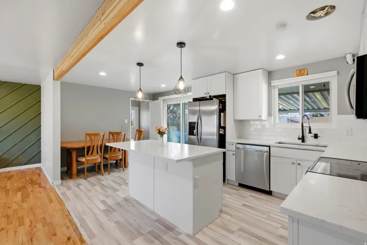 Kitchen featuring white cabinets, stainless steel appliances, pendant lighting, a center island, and light wood finished floors