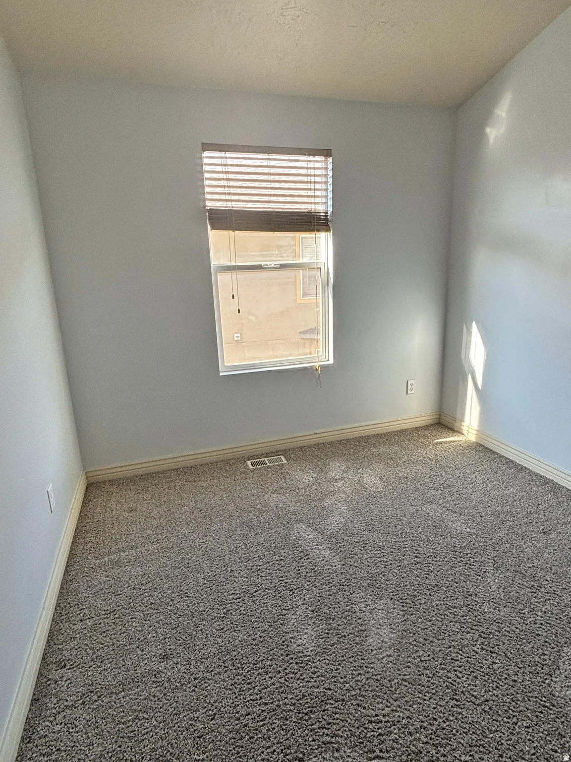 Carpeted empty room with baseboards and a textured ceiling