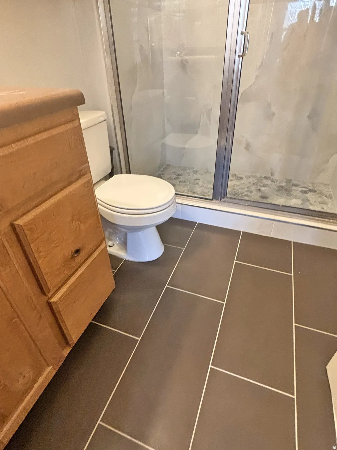 Bathroom with a stall shower and dark tile patterned floors