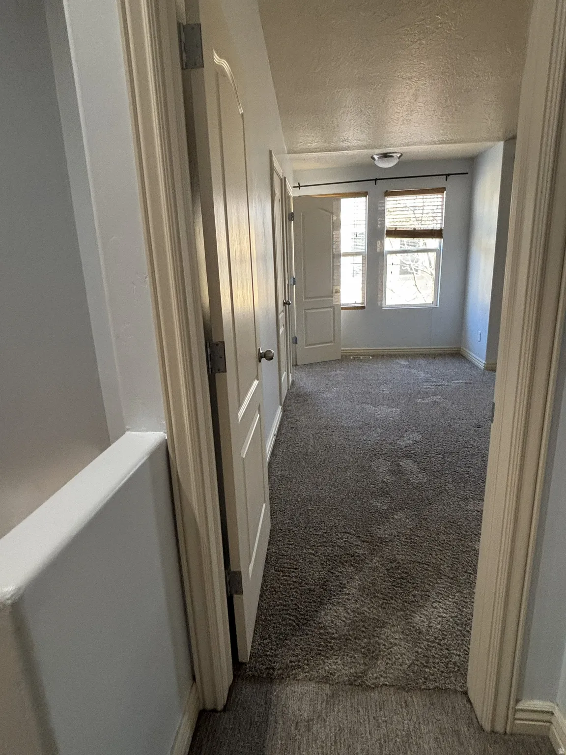 Corridor featuring carpet flooring and a textured ceiling