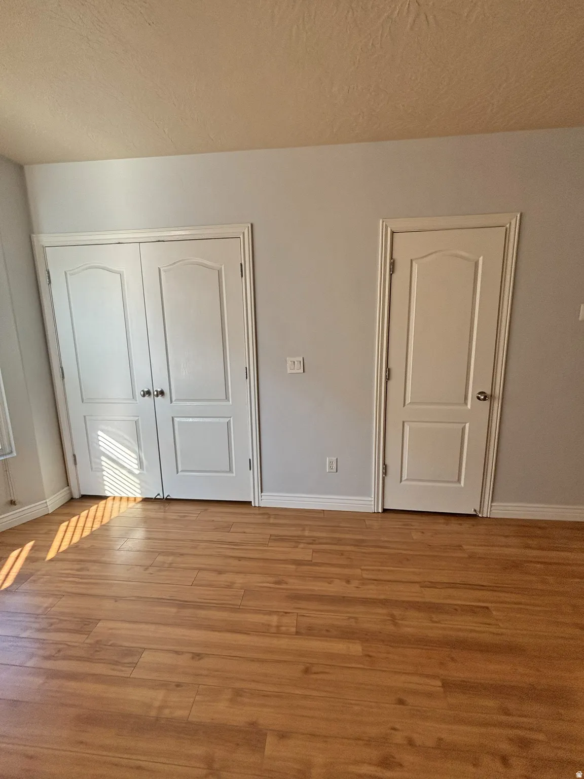 Unfurnished bedroom featuring light wood finished floors, a closet, and a textured ceiling