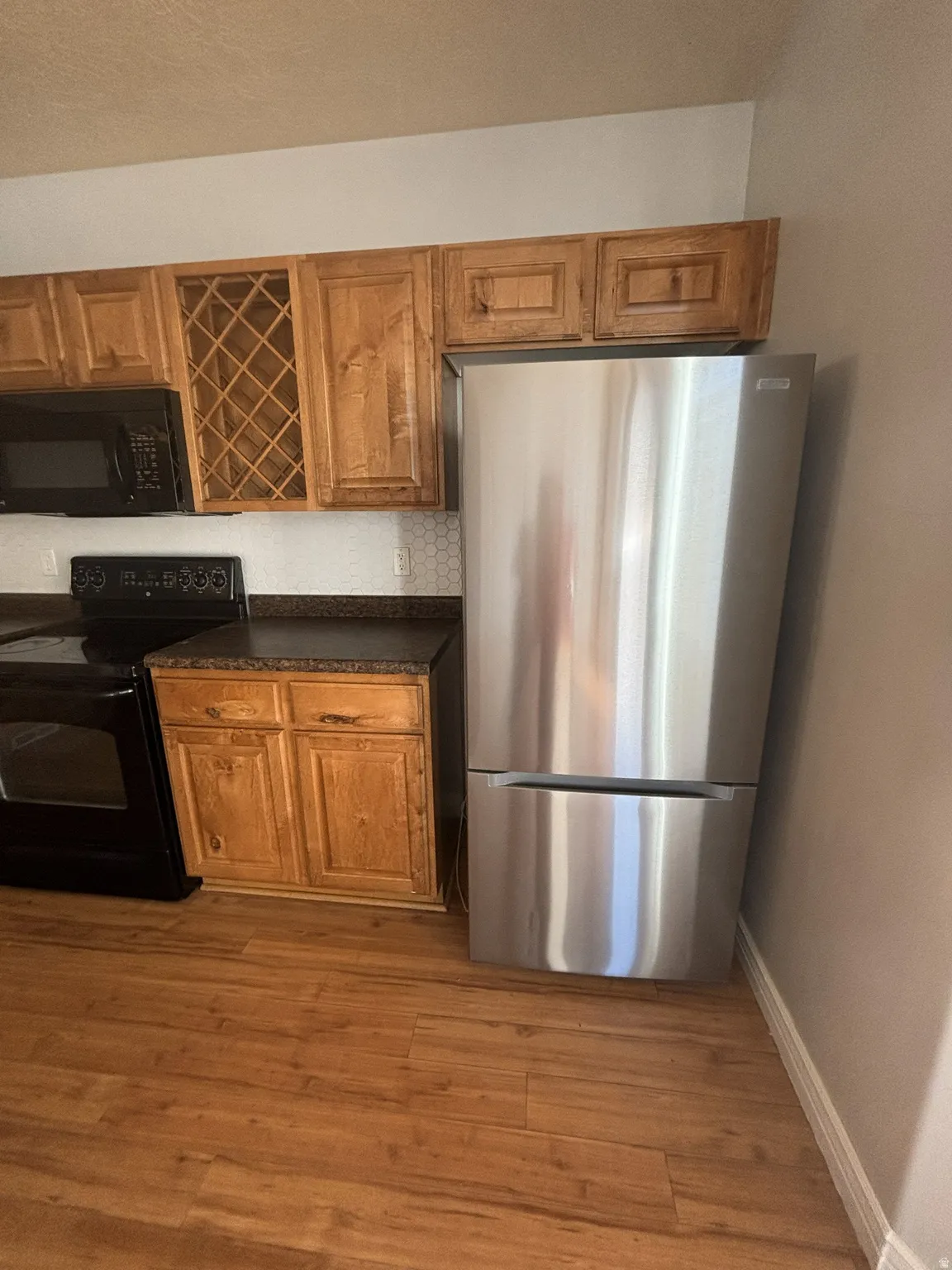 Kitchen featuring black appliances, brown cabinetry, and light wood finished floors