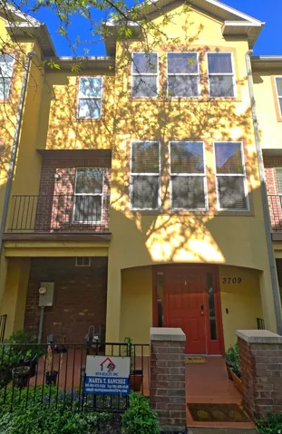 View of front of property with brick siding, a balcony, and stucco siding