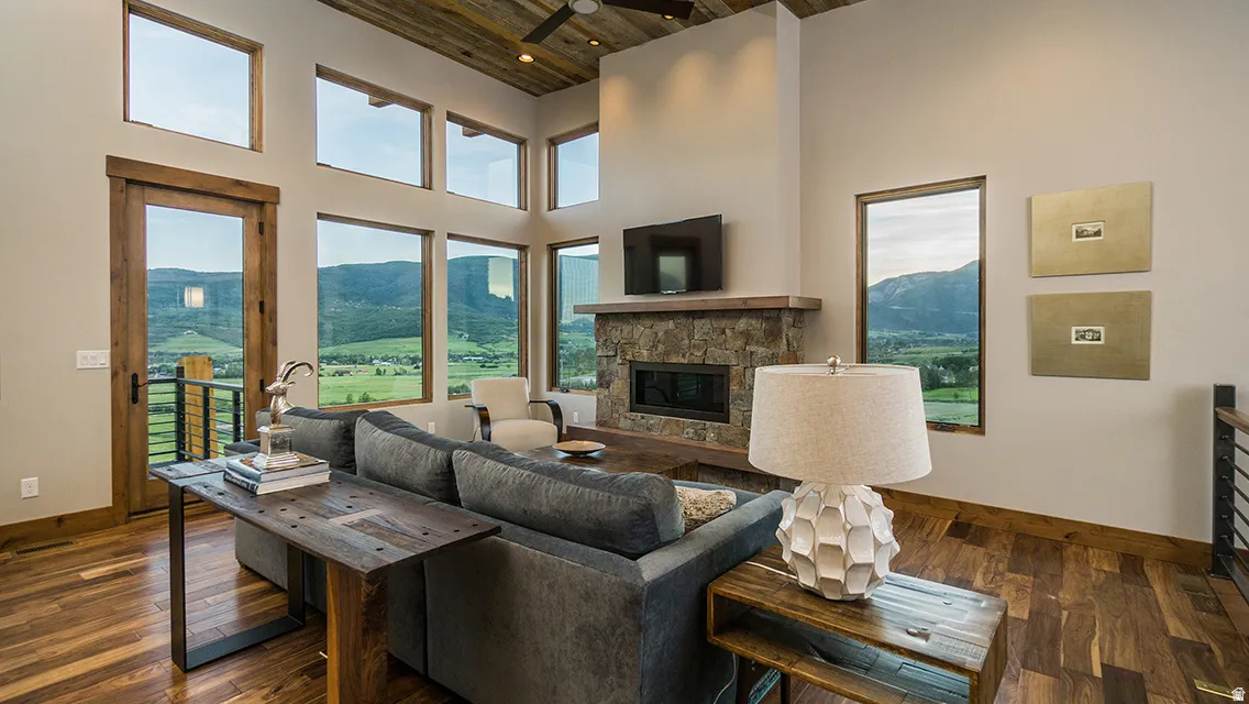 Living area featuring dark wood finished floors, wood ceiling, a fireplace, and a towering ceiling