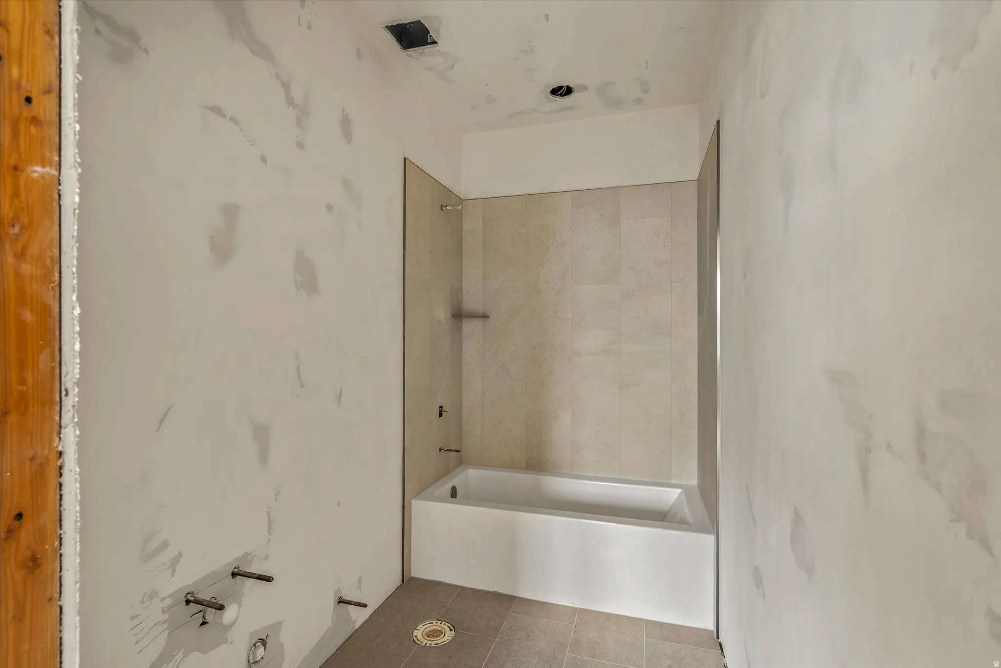 Newly installed bathtub with tile surround and glass partition