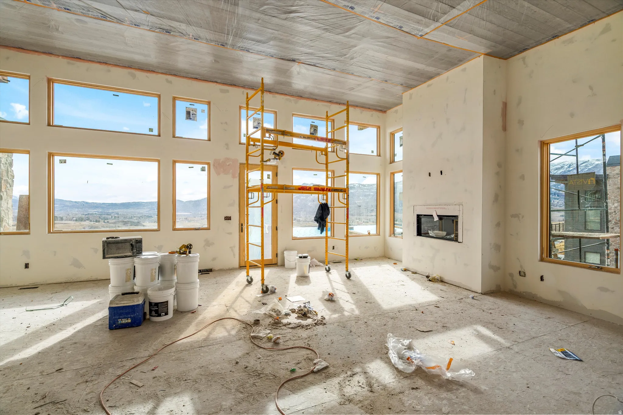 Spacious room under construction featuring numerous windows, a built-in fireplace, and high ceilings