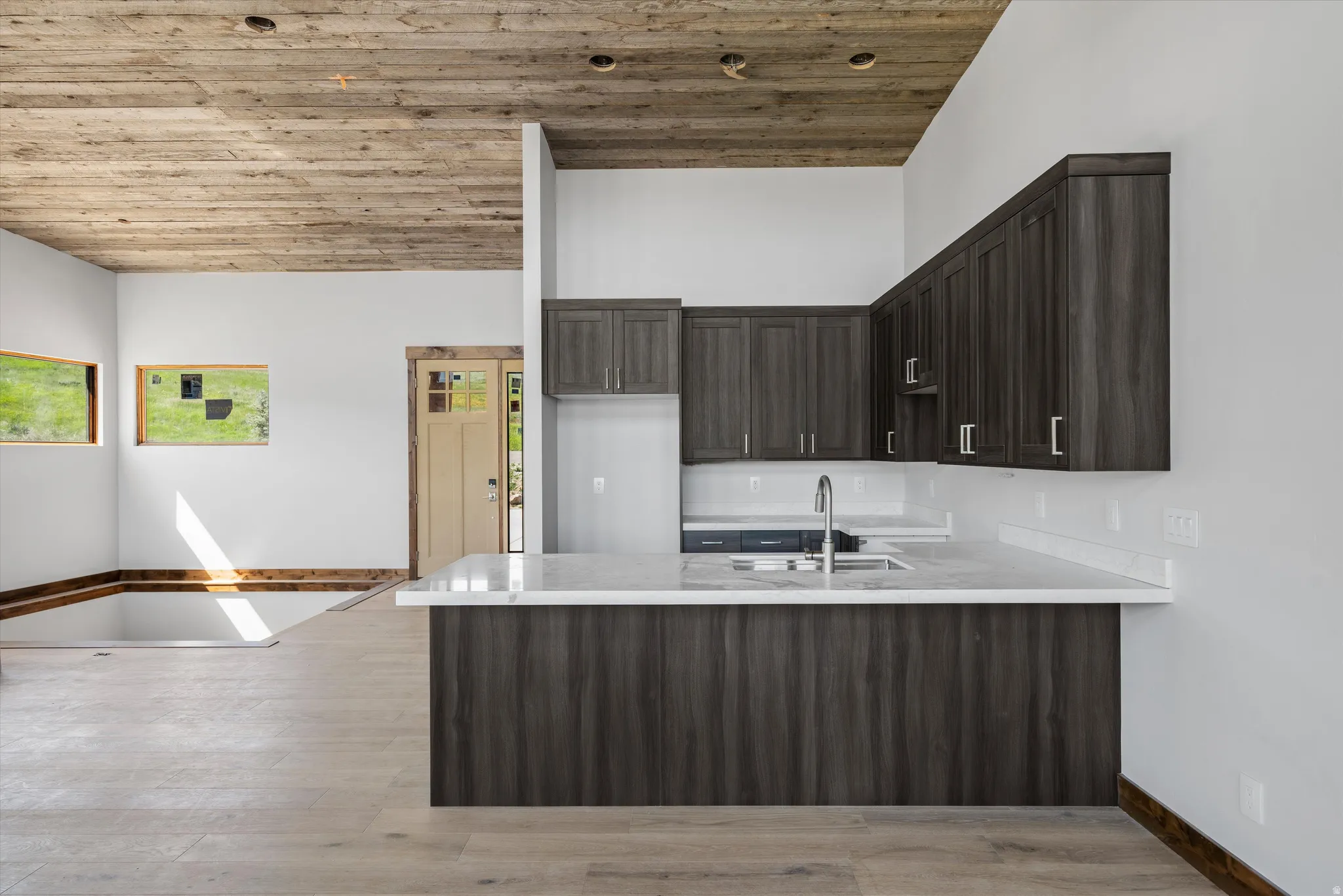Modern kitchen with dark wood-finish cabinetry, light-toned countertops, and a stainless steel sink