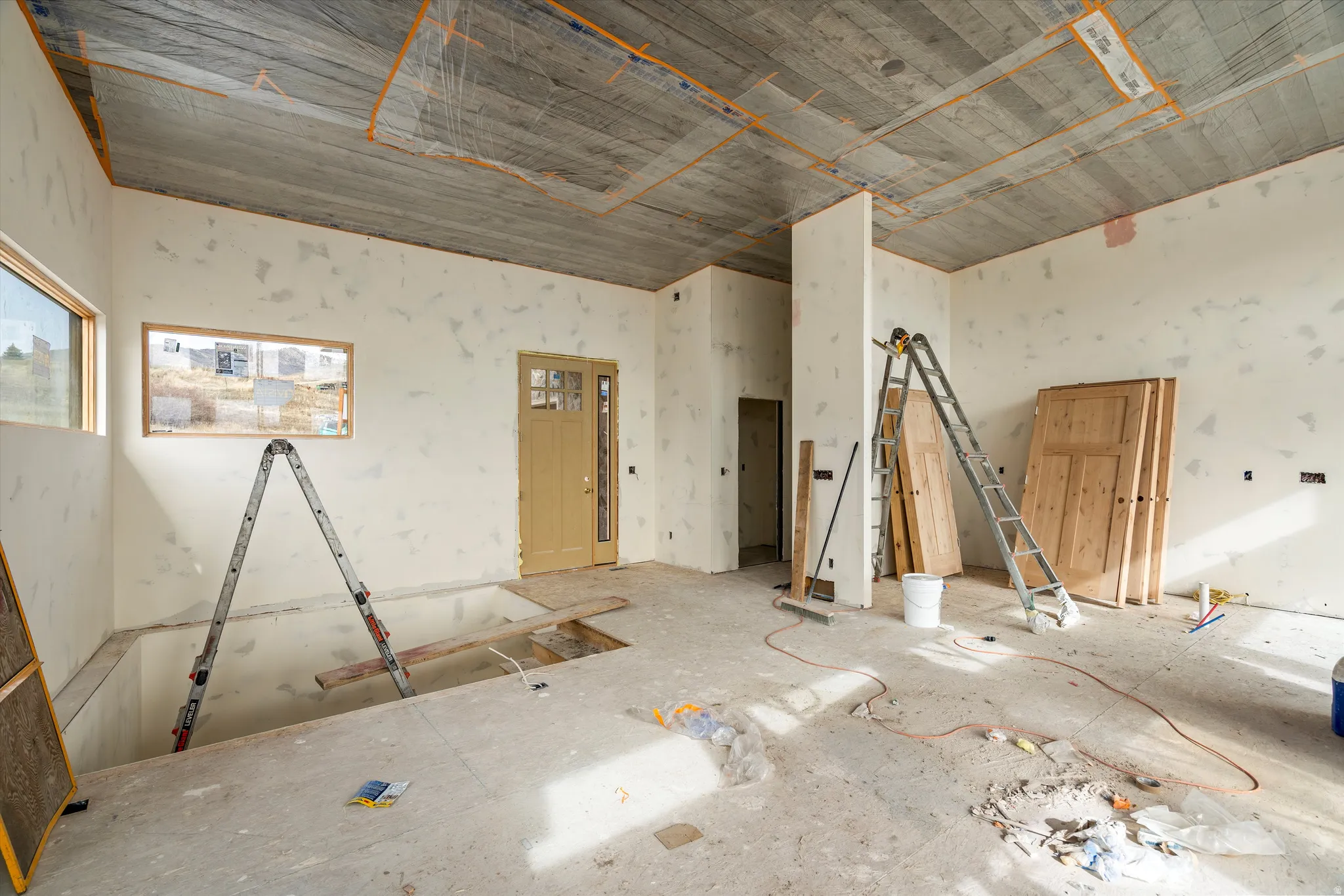 Entryway featuring a partially finished ceiling, two distinct window openings, a light-colored entry door with glass panels, and an open floor plan