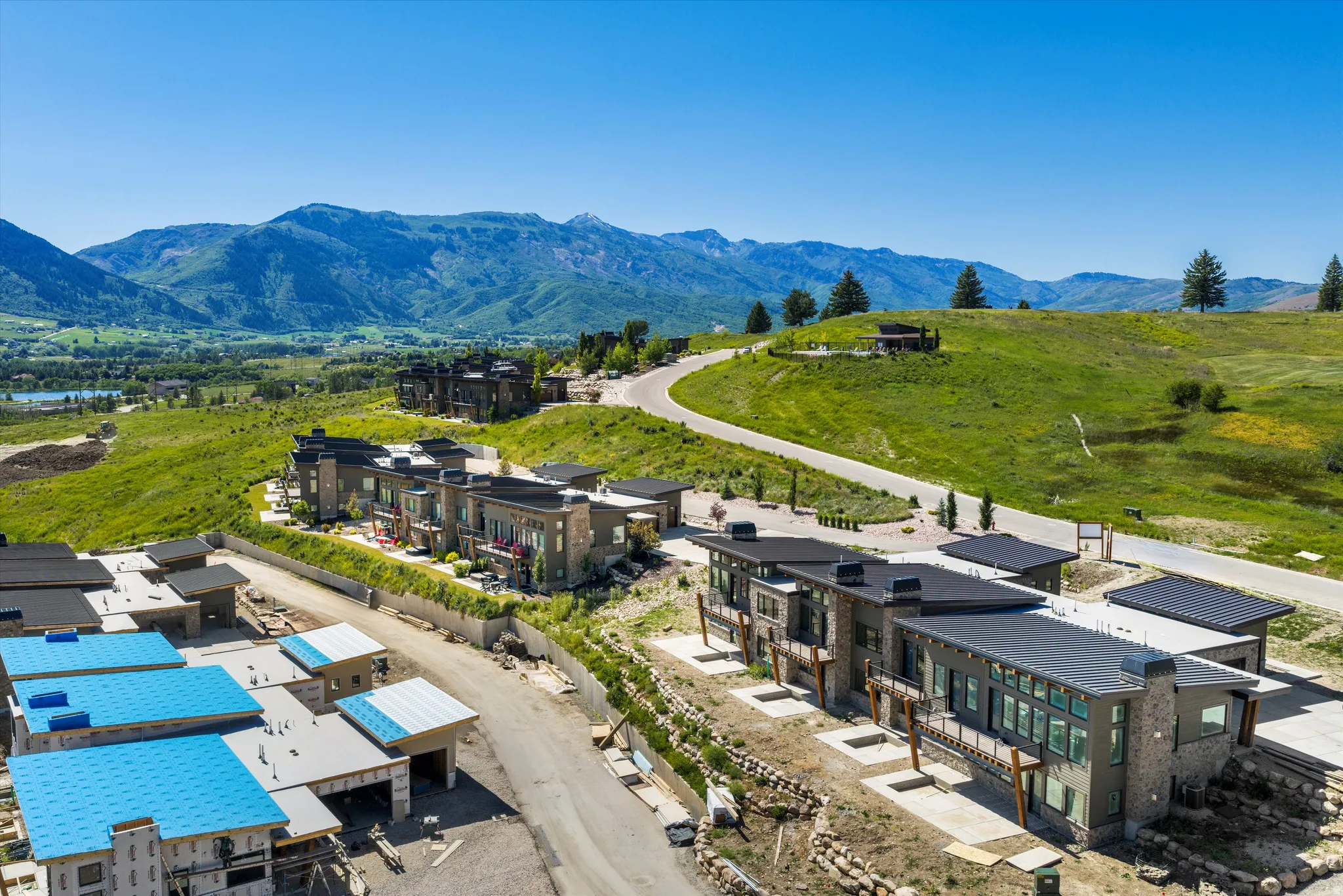 Contemporary residences featuring expansive windows, stone accents, and dark-pitched roofs