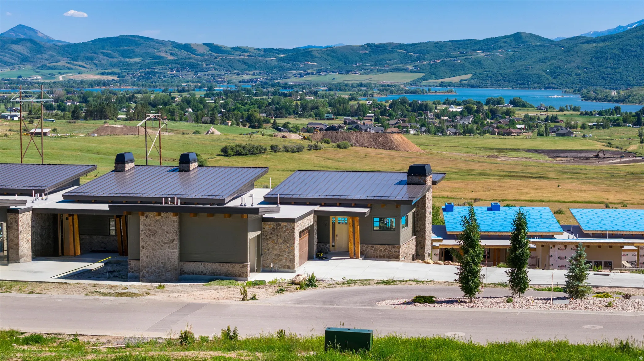 Modern architectural design featuring a flat metal roof, stone facade, and a prominent wood-finished front entry