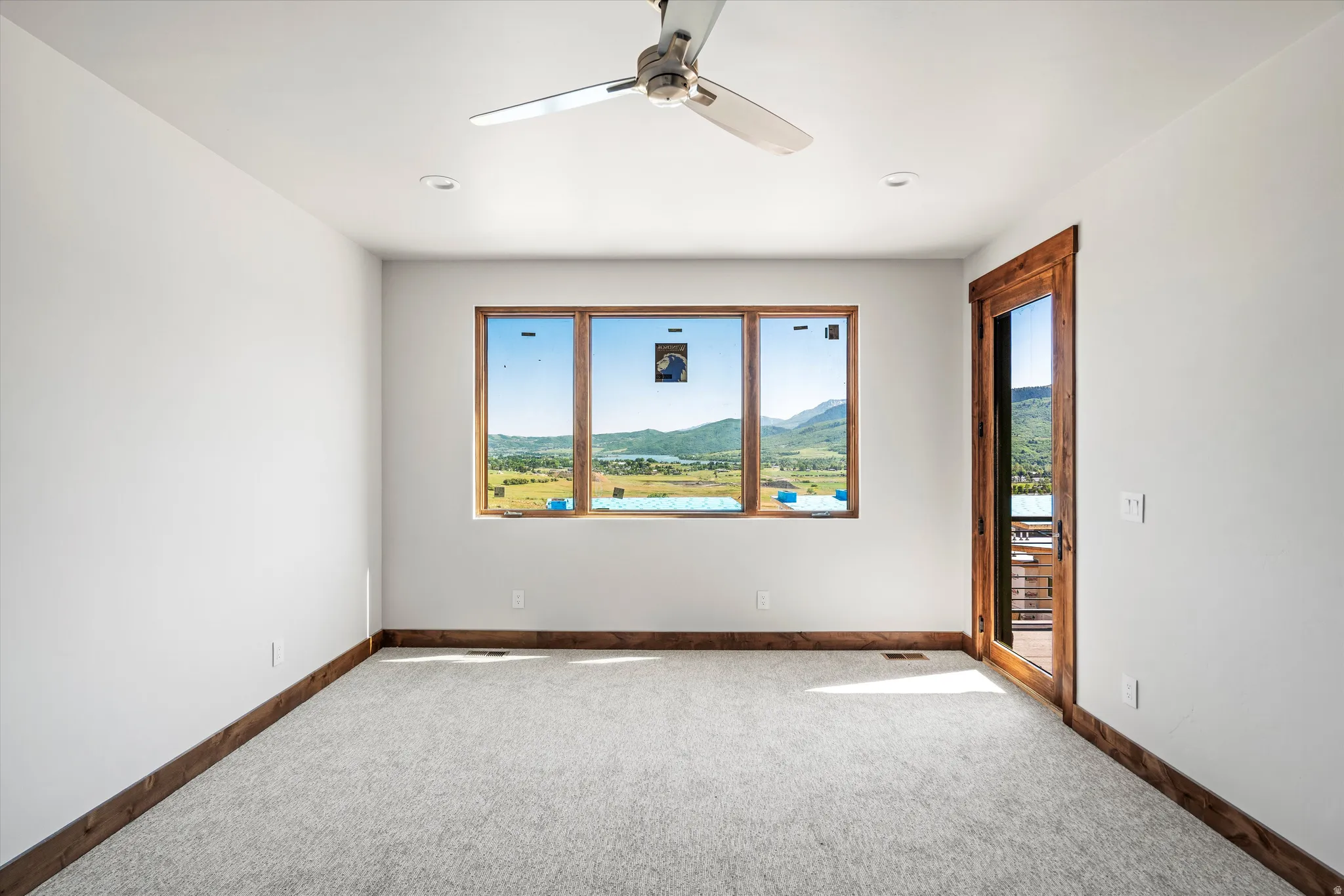 Spacious room featuring broad picture windows, a wood-framed glass door, and recessed lighting
