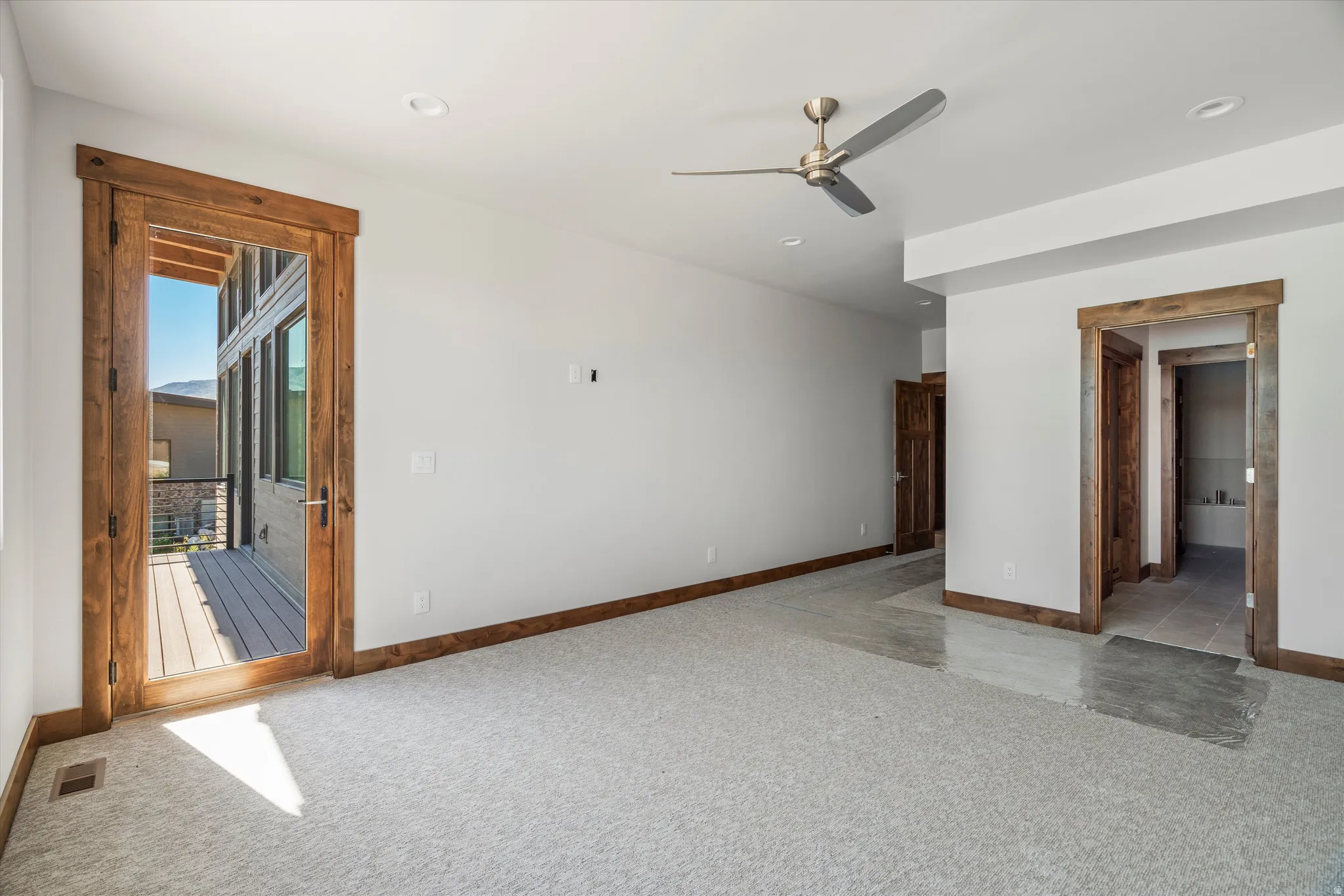 Spacious room with light-colored carpeting, recessed lighting, and a contemporary ceiling fan
