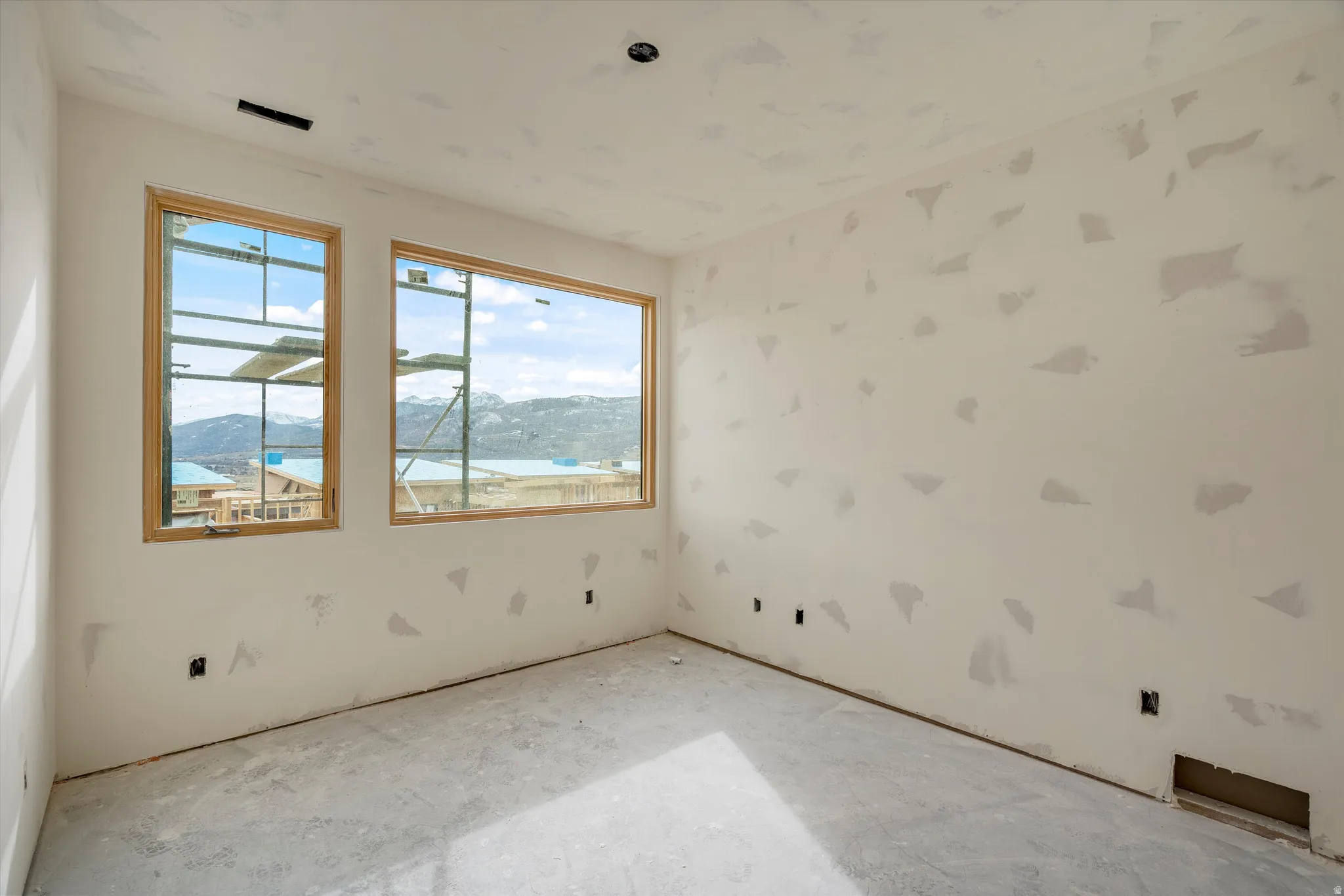 Room with two large windows showcasing distant mountains and a body of water