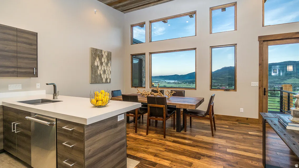 Kitchen featuring dark brown cabinets, modern cabinets, dark wood-style floors, a peninsula, and a towering ceiling