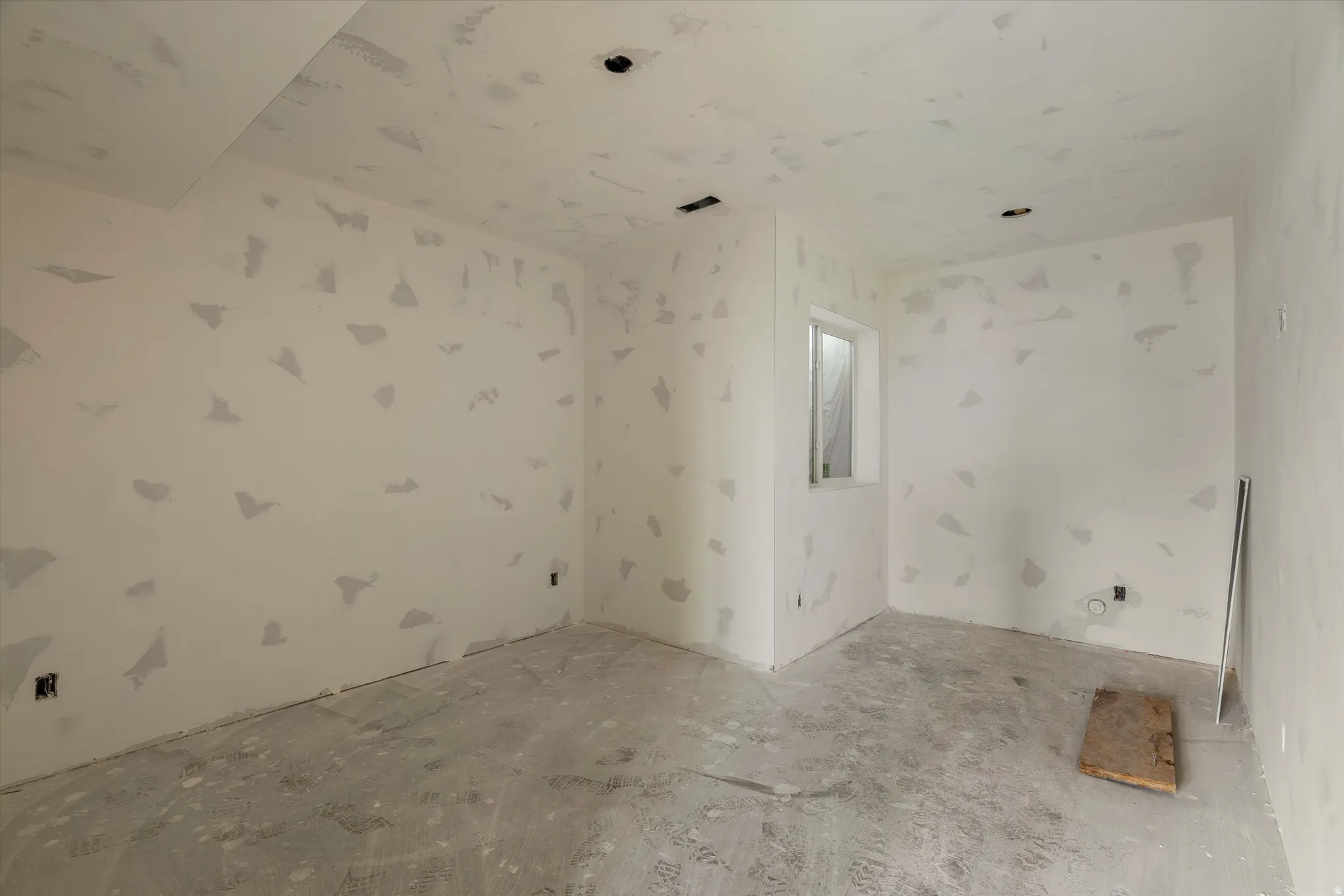 Unfinished room with natural light, featuring a single window, recessed lighting rough-ins, and a concrete floor