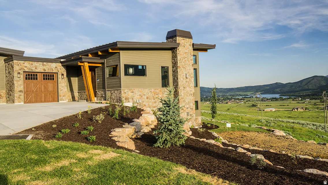 View of front of property with stone siding, concrete driveway, a mountain view, a garage, and a front yard