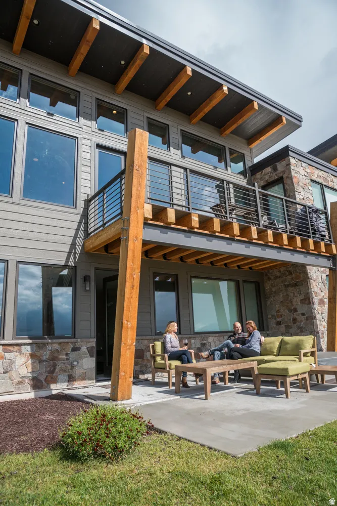 Back of property with outdoor lounge area, stone siding, and a patio area