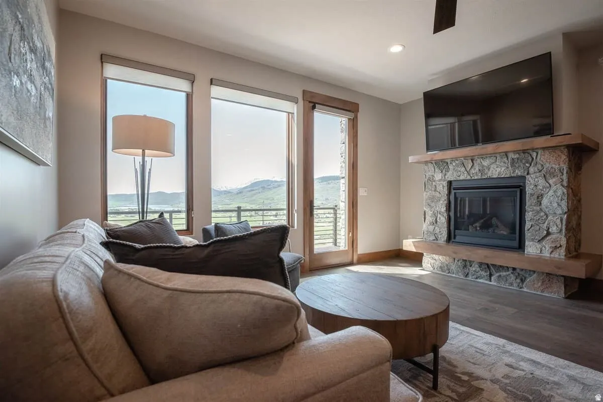 Living area featuring a stone fireplace, wood finished floors, recessed lighting, and a ceiling fan