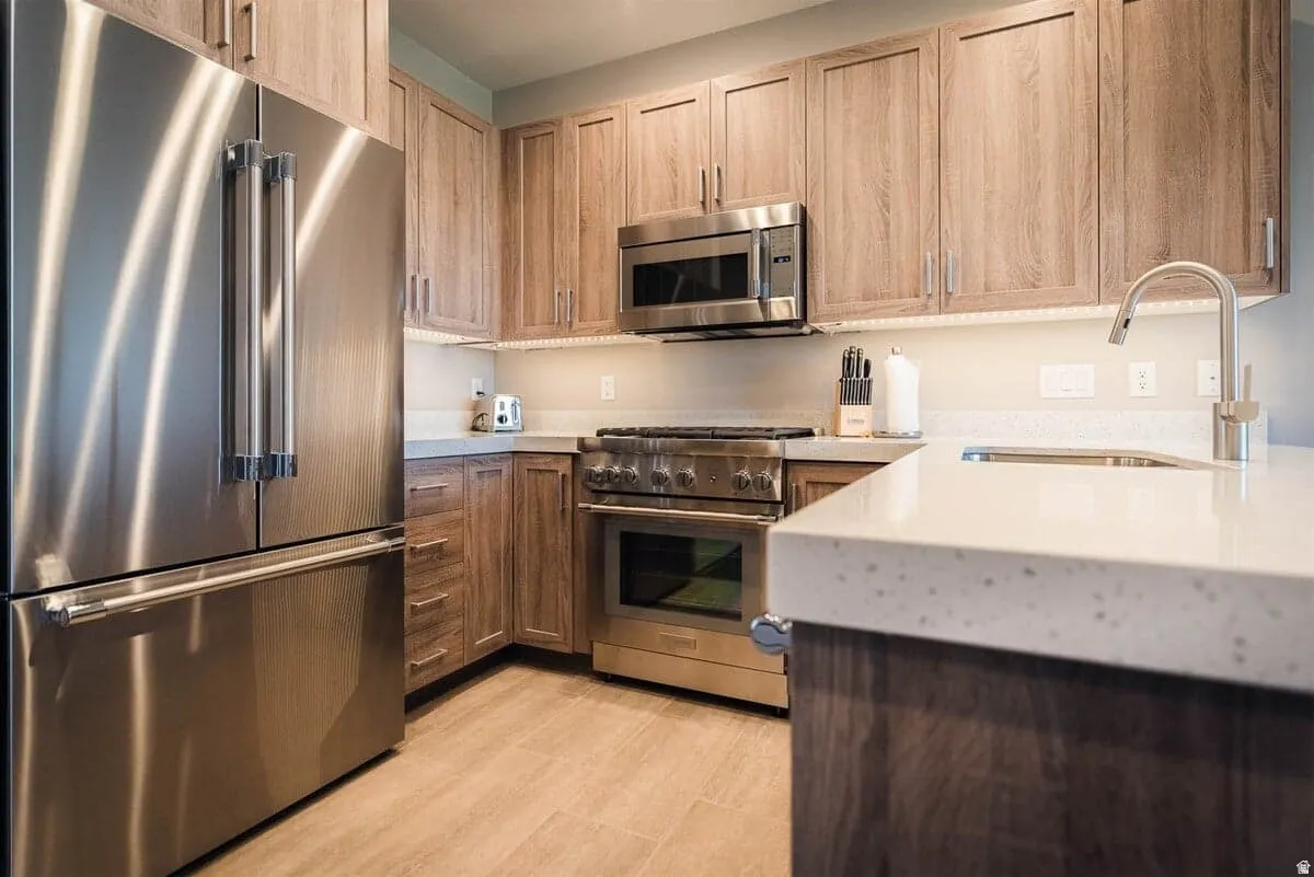 Kitchen featuring high end appliances, light stone counters, and light wood-type flooring