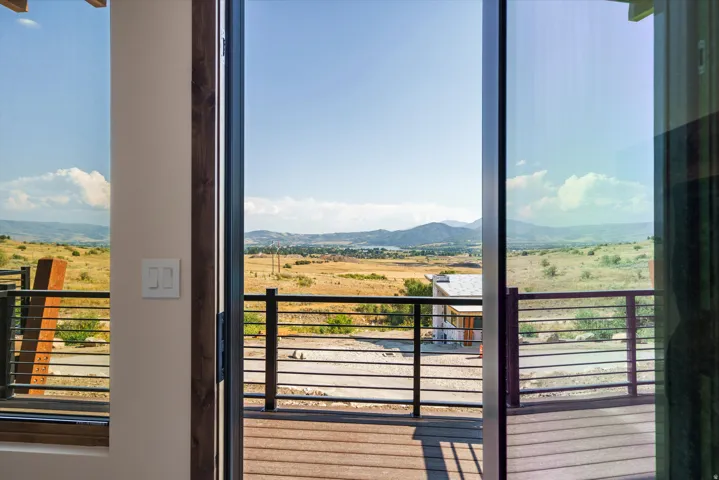 Expansive deck with horizontal metal railings overlooking expansive open land and distant mountain ranges
