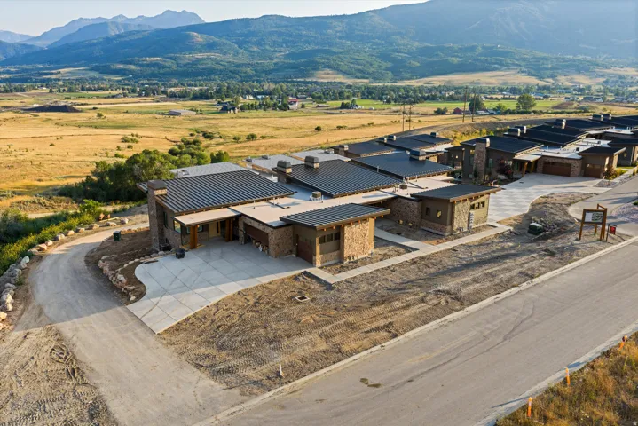 Modern architectural design featuring varied rooflines, stone and wood-panel accents, and an integrated garage