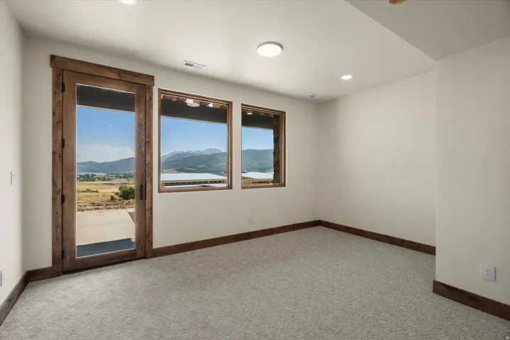 Bright, light-filled room featuring expansive windows with wood-finish frames offering panoramic mountain and valley vistas