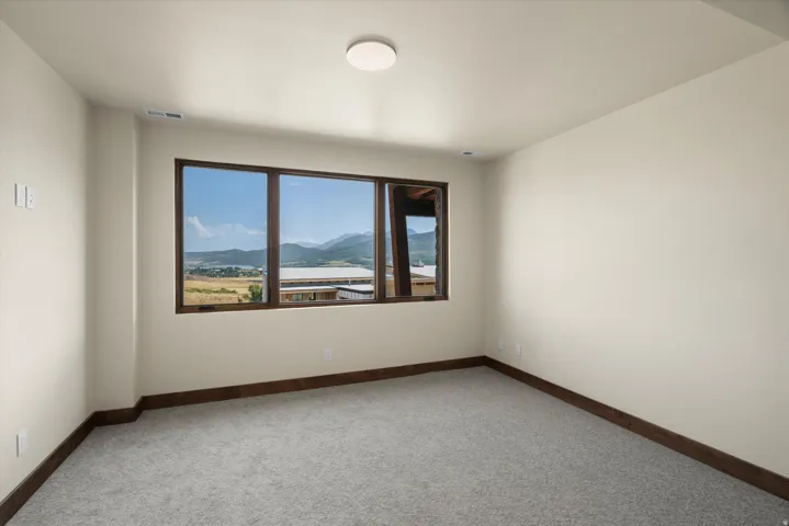 Bright corner bedroom with expansive triple-pane windows framing scenic mountain and valley vistas