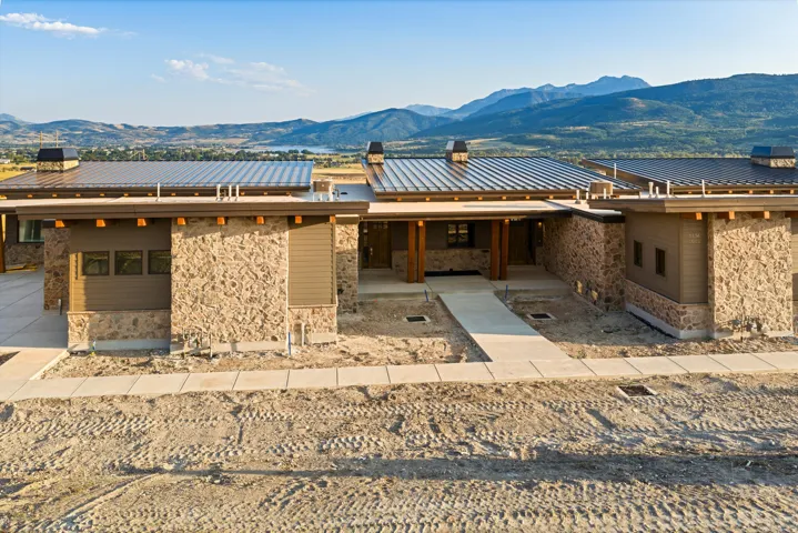 Spacious exterior featuring a stone facade, metal roofing, exposed wood beams, and an extended covered entry