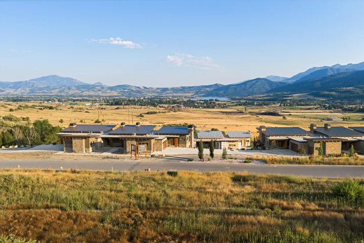 Modern agricultural or equestrian facility featuring a substantial single-story structure with multiple connected sections and dark metal roofing