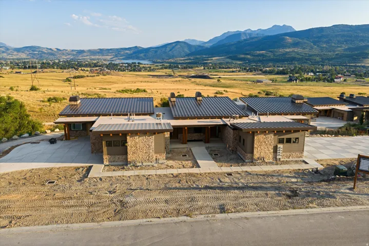 Contemporary stone and metal residence showcasing a striking architectural design with multiple pitched metal rooflines and substantial stone chimney elements
