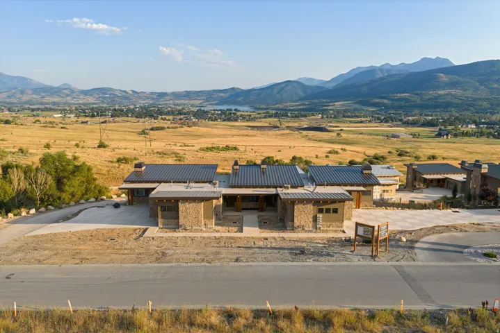 Modern residential compound featuring a striking contemporary design with stone and wood-finish exterior materials, topped with a standing-seam metal roof
