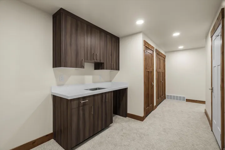 Utility area featuring dark wood-finish cabinetry, a light-toned countertop, and an undermount stainless steel sink