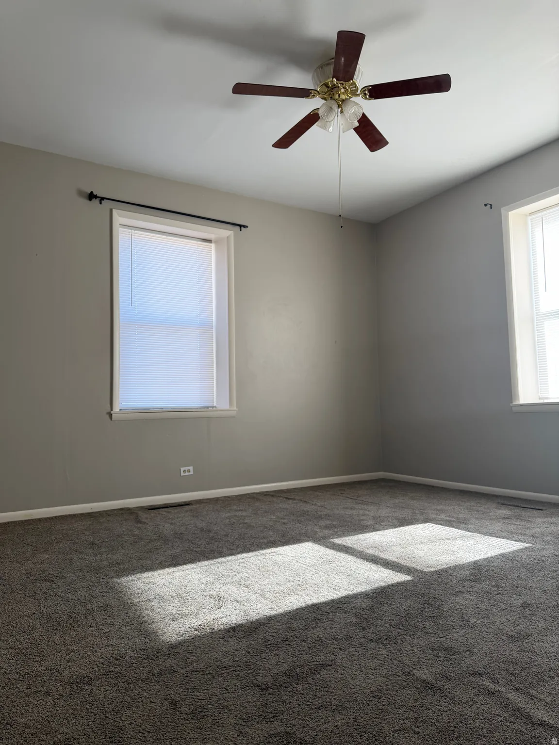 Carpeted empty room featuring ceiling fan