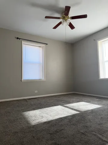 Carpeted empty room featuring ceiling fan